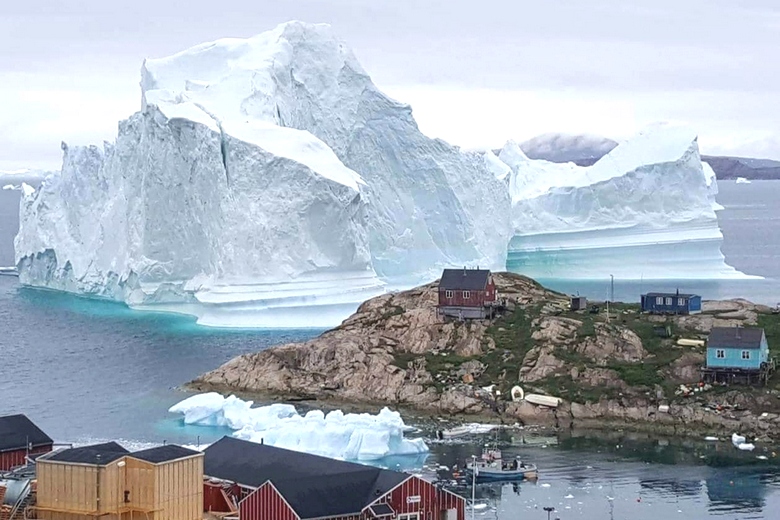 Iceberg gigante a strapiombo su un villaggio in Groenlandia