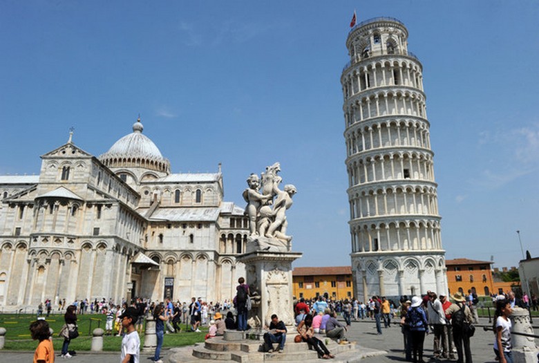 Numerosi turisti livellano gradualmente il pendio della Torre pendente di Pisa.